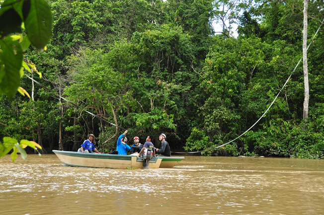 A group of HUTAN and Chester Zoo conservationists travel along the Kinabatangan river in a green and white boat