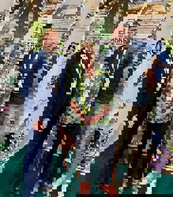 Three people in smart casual dress standing in front of a series of images in the Reverse the Red pavilion