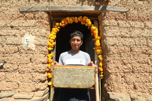 A man living in Tajira. He's standing in a door weigh with a heavy frame of honeycomb